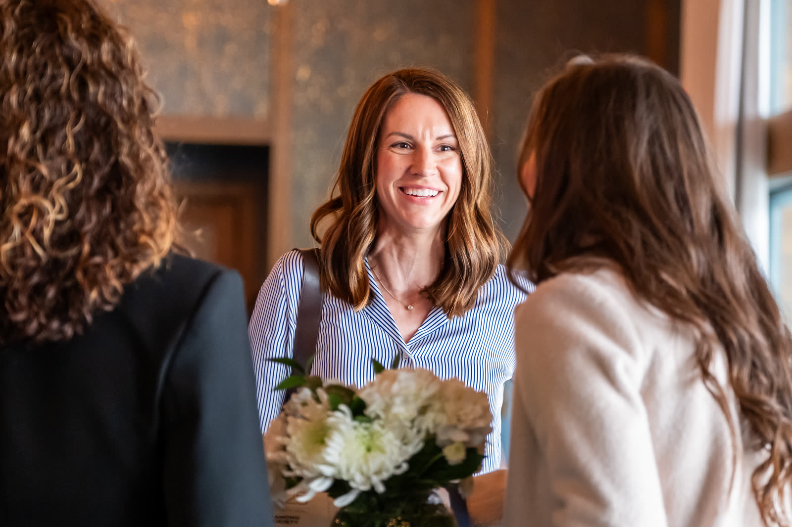 A smiling honoree holding a bouquet of white flowers at an awards luncheon