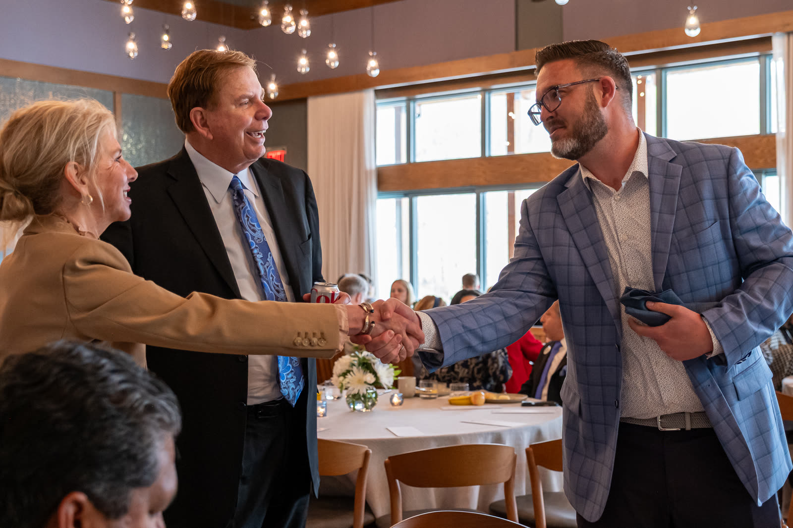 A congratulatory handshake across a banquet table at an awards luncheon