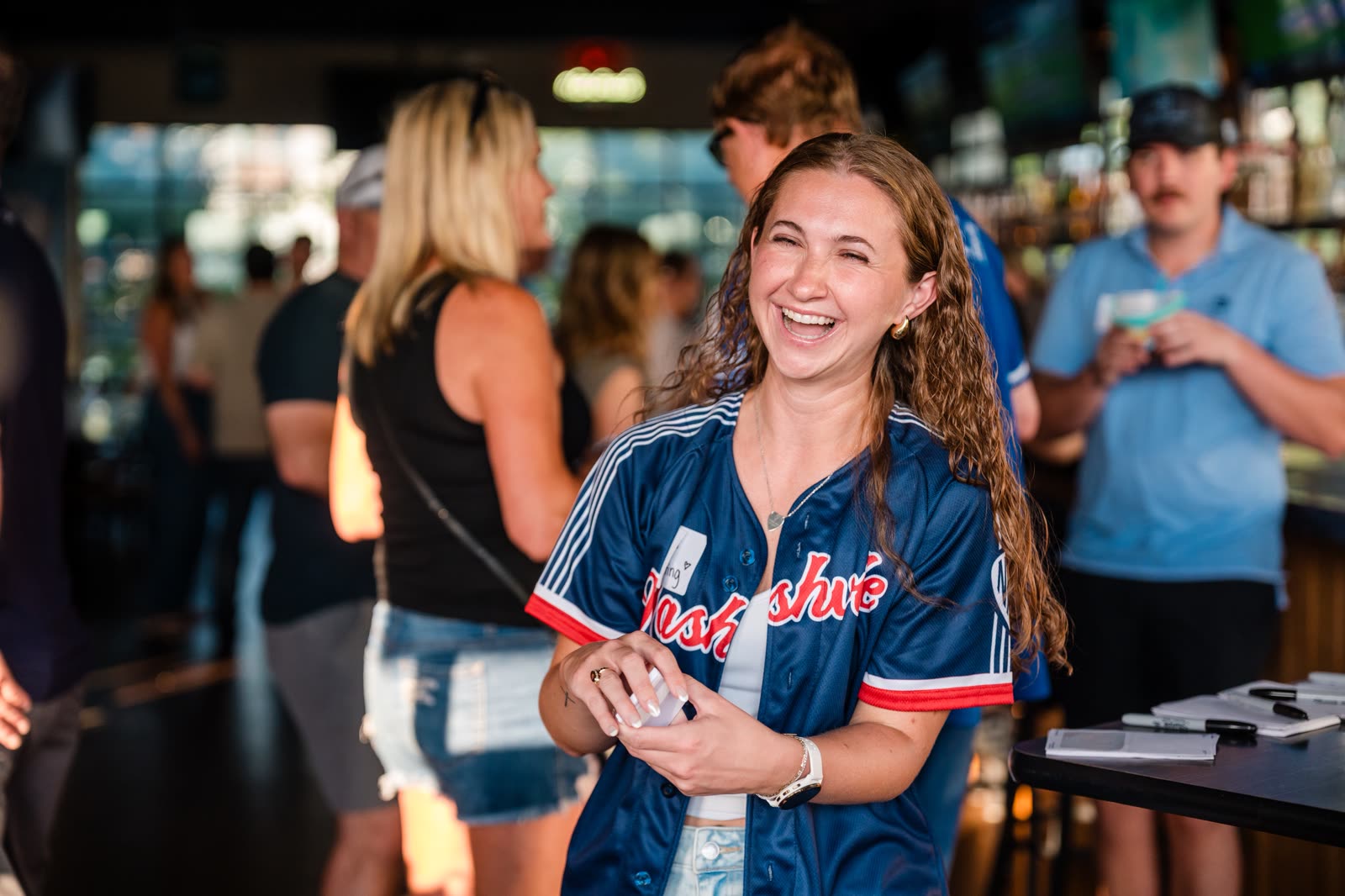 A guest in a Nashville jersey laughing during a company gathering at the ballpark