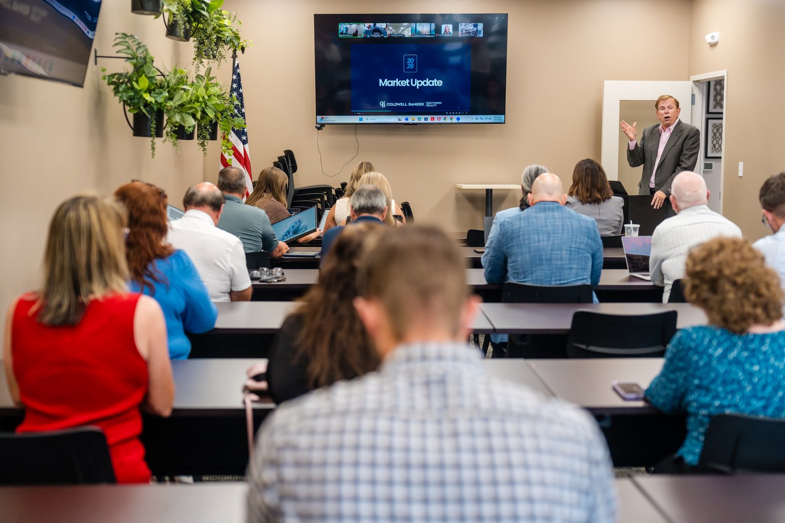 A presenter addressing a full room during a market update session