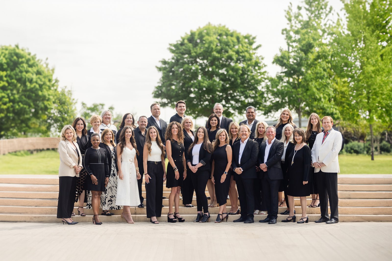 A full brokerage team photographed together on steps outdoors