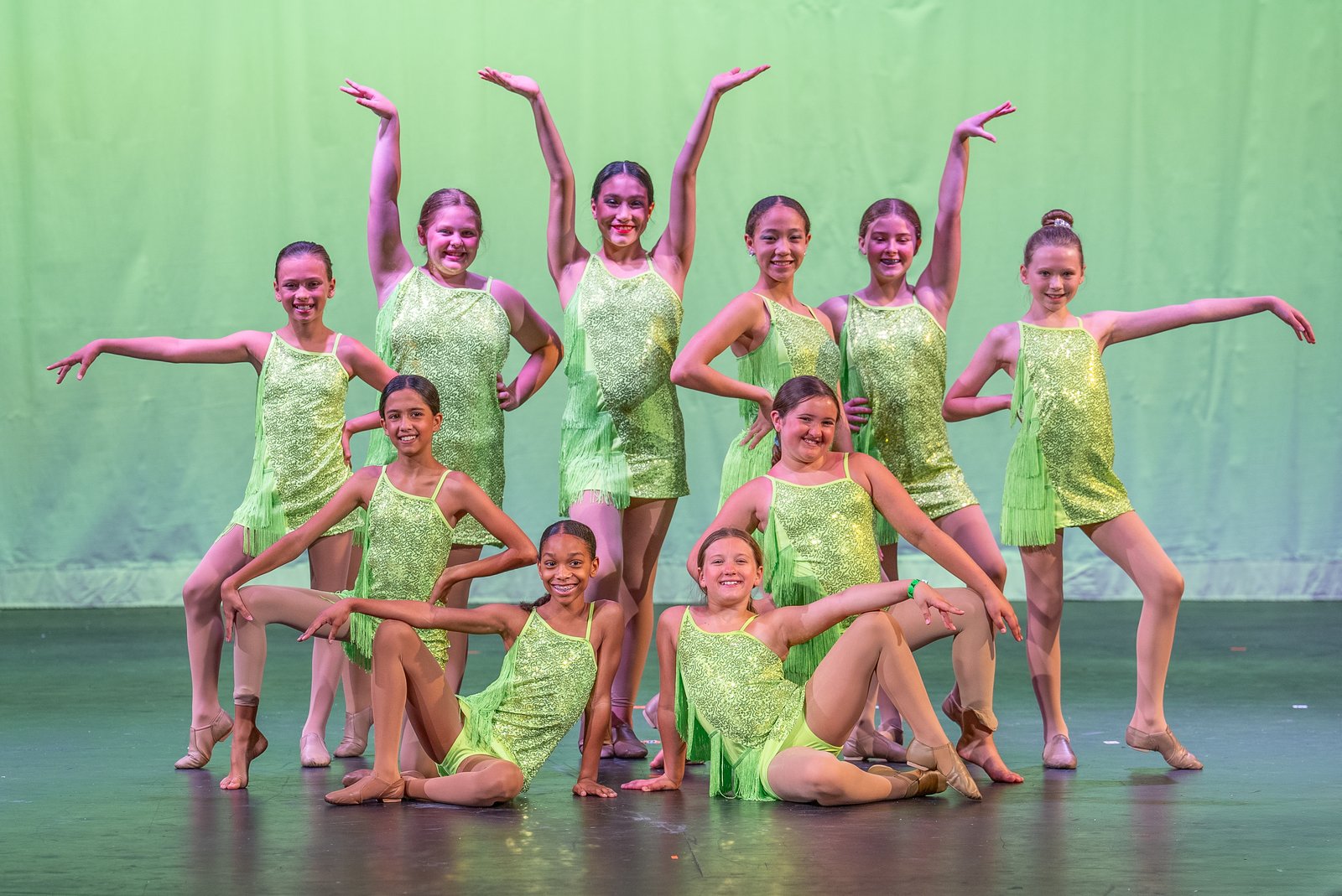 A jazz group in green fringe costumes posed under green light