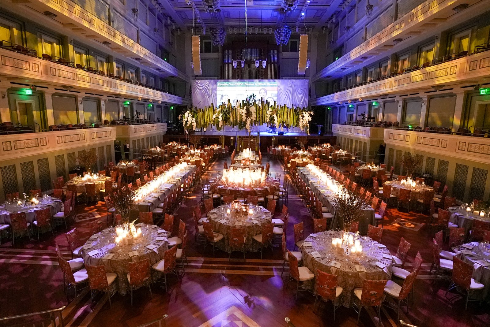 A gala ballroom set for dinner, seen from the balcony before guests arrive
