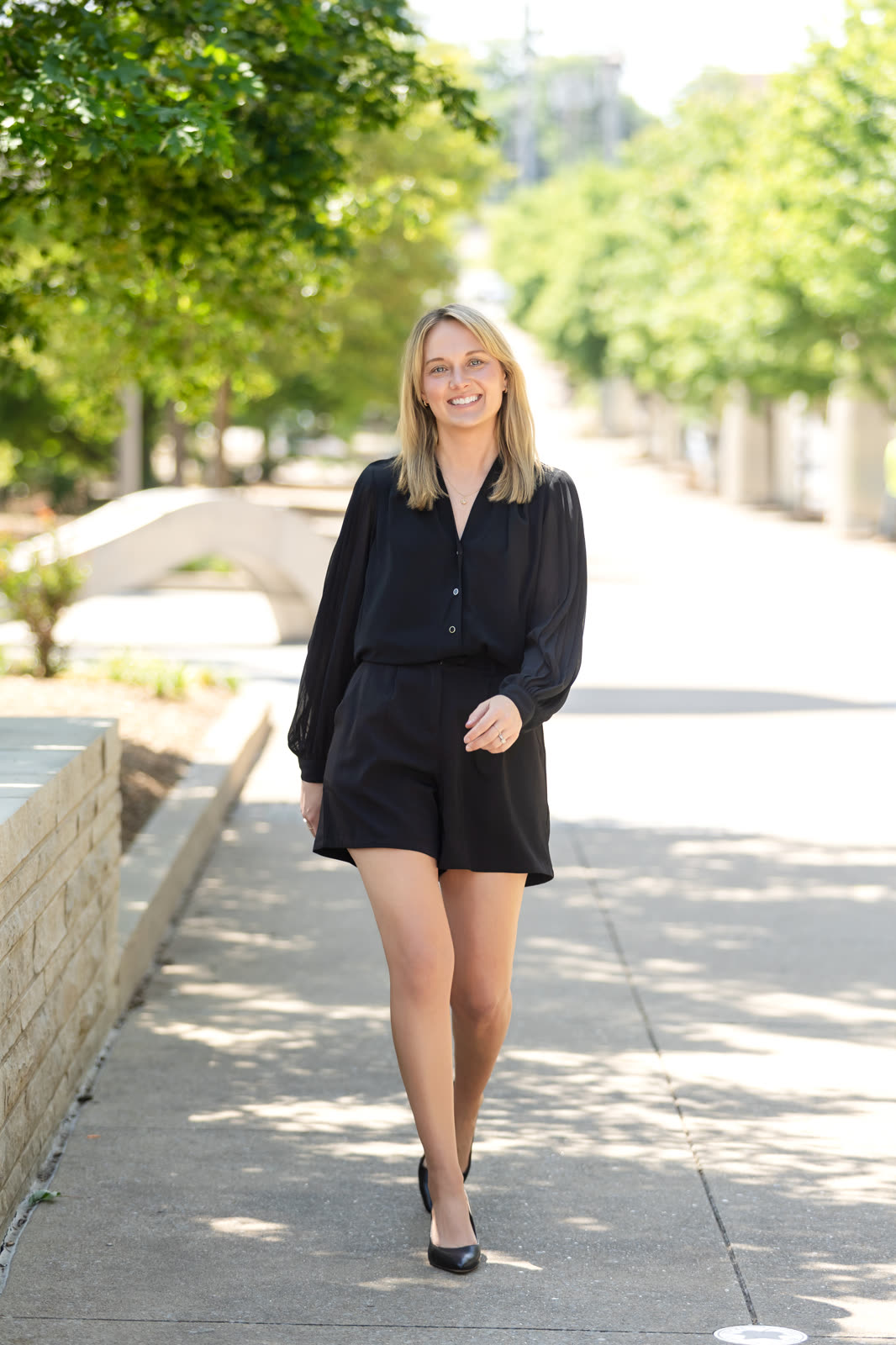 A team member in black walking a tree-lined path