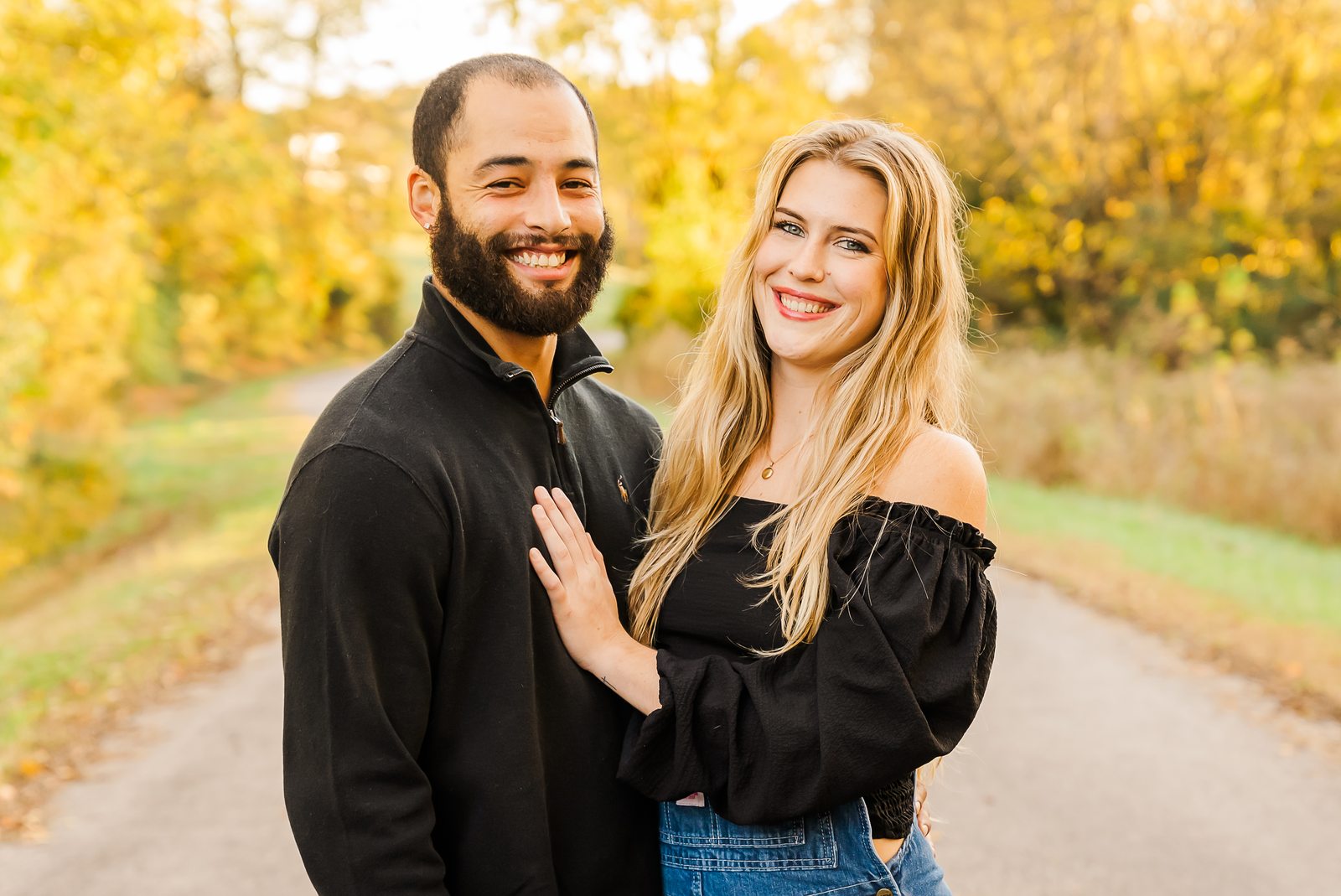 Parents kissing their laughing baby's cheeks on an autumn lane