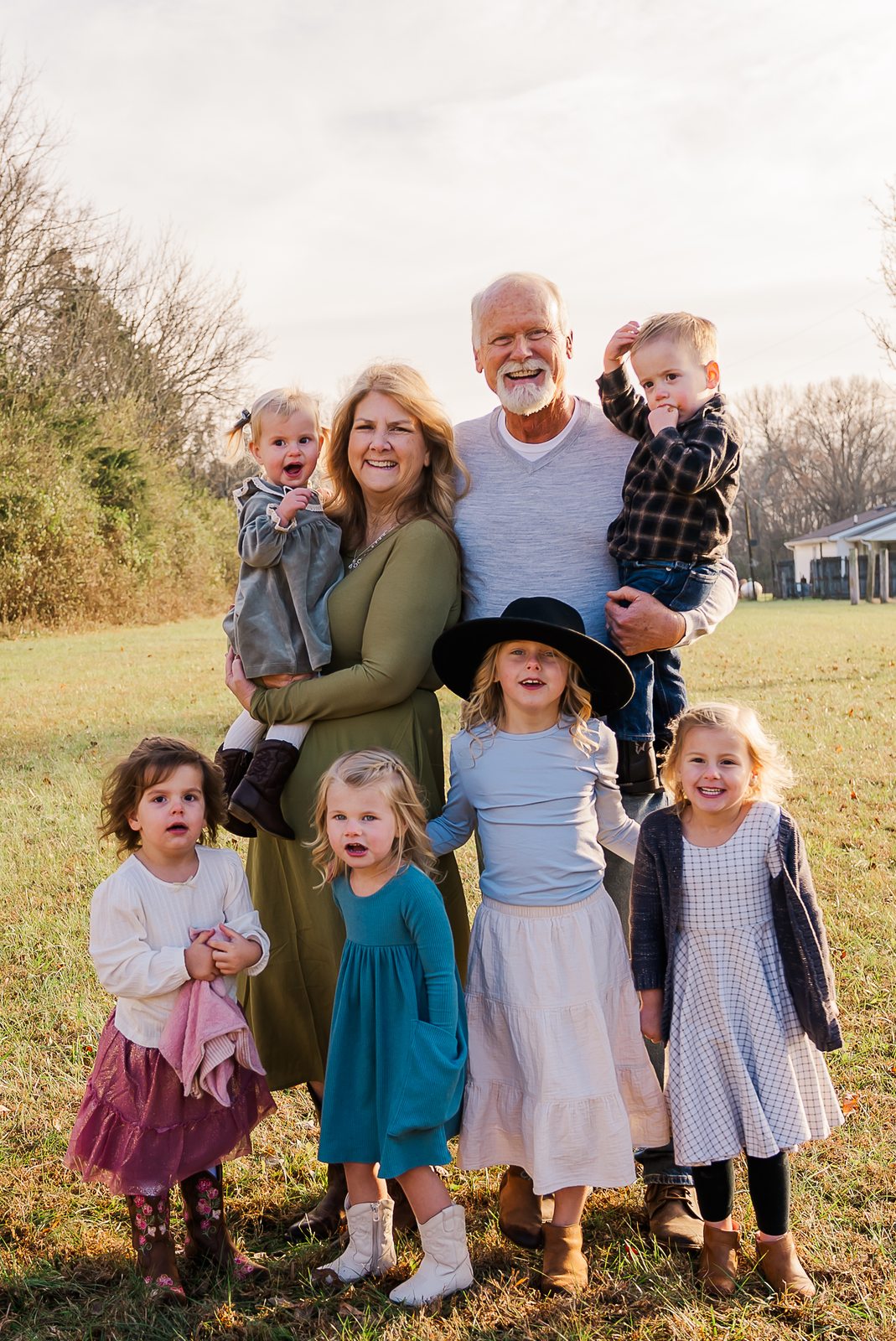 Grandparents surrounded by six grandchildren in a winter field