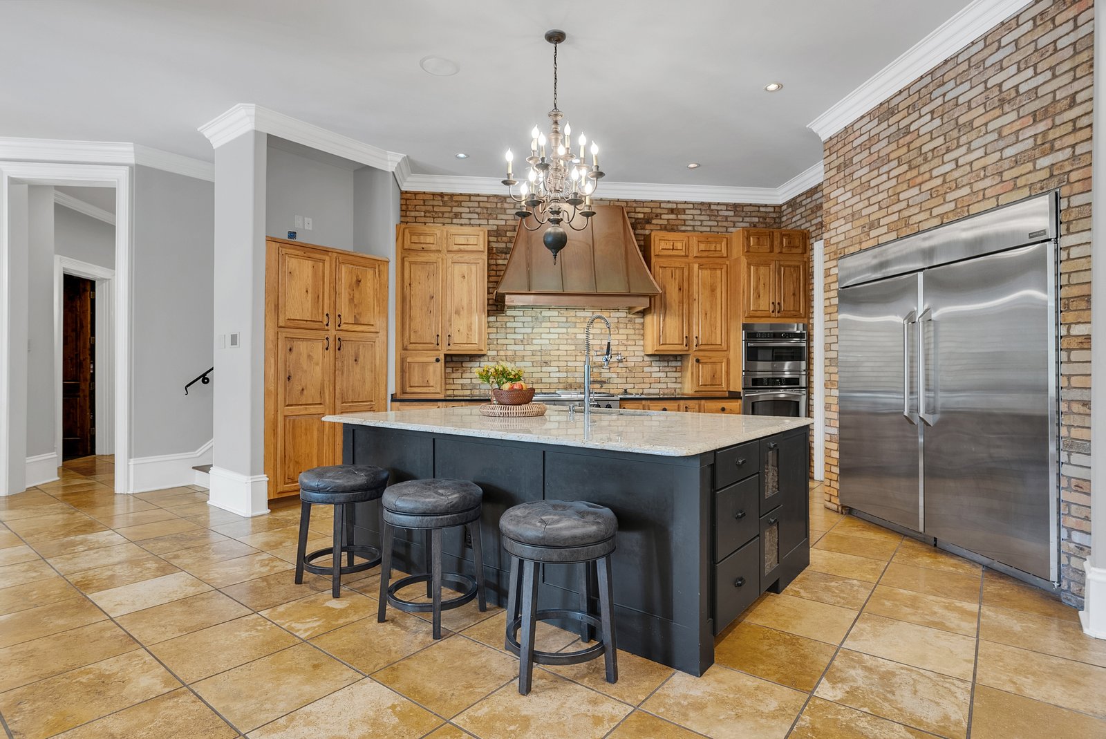 A kitchen island with seating, brick walls and stainless appliances