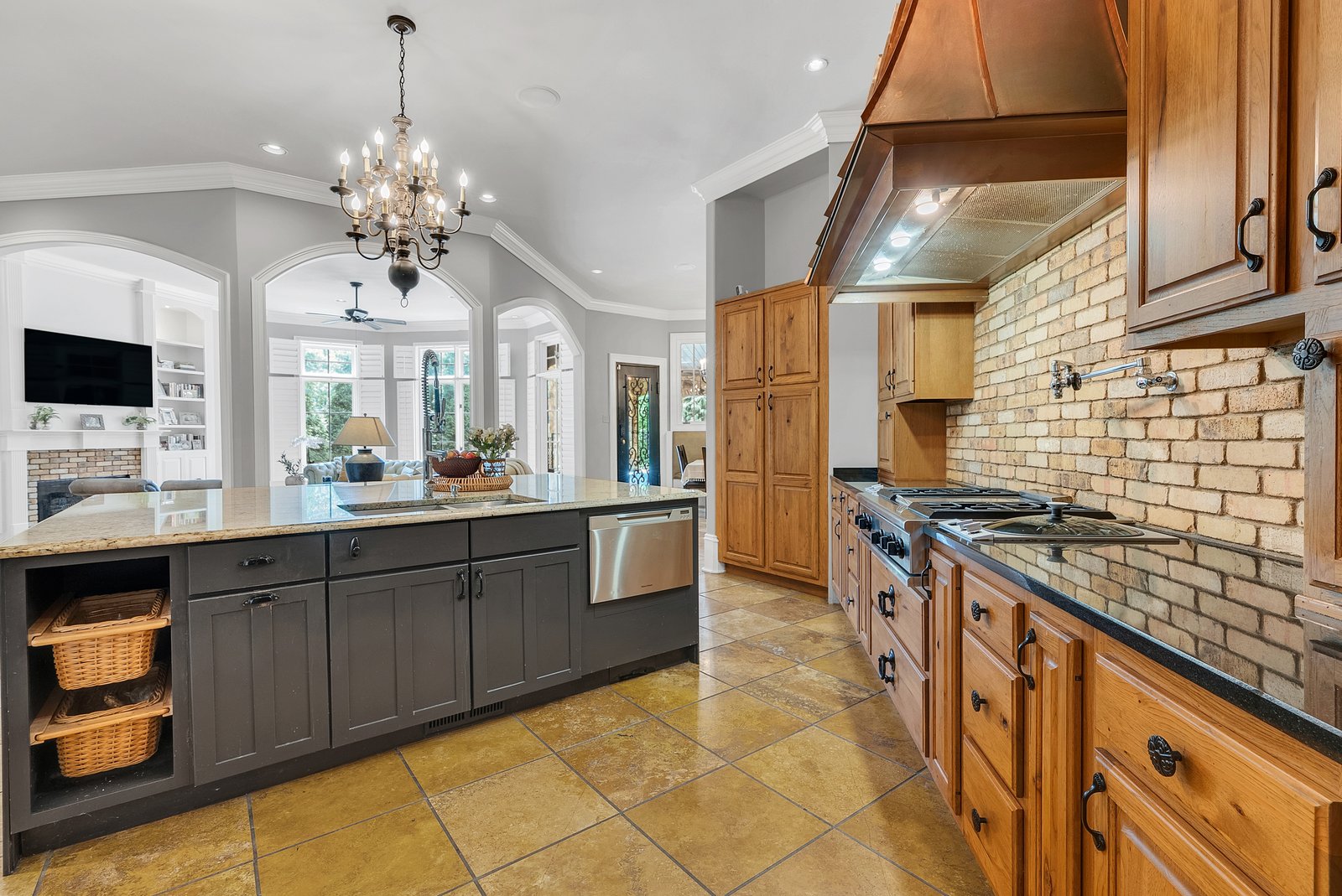 A kitchen with a copper hood and brick backsplash, colour corrected