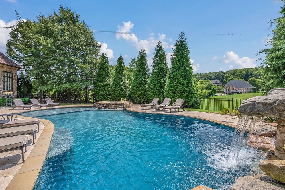 A curved pool with a rock waterfall and loungers