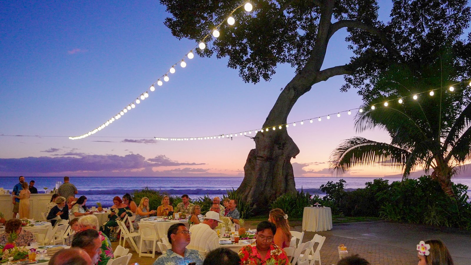 A beachside wedding reception under string lights after sunset